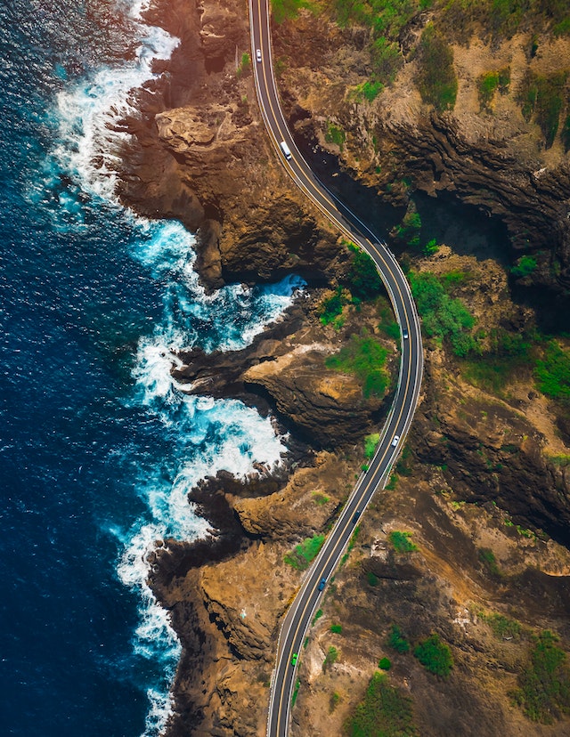 Scenic coastal road winding along cliffs beside the ocean, ideal for road trip travel experiences.